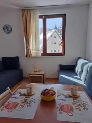 a living room with a table with a bowl of fruit at Kopaonik apartman 11 in Kopaonik