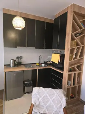 a kitchen with a counter with a sink and a shelf at Apartmani Krunet in Kruševac