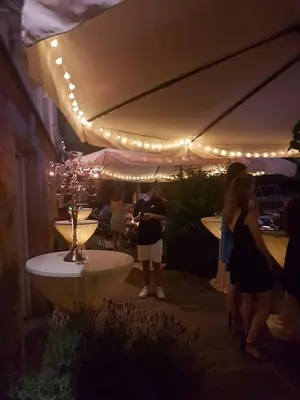 a group of people standing around a patio with lights at Luxury Rooms Minjon in Vrnjačka Banja