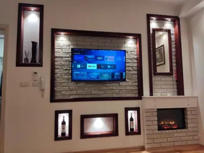 a living room with a tv on a brick fireplace at Apartmani Stanković in Vranje