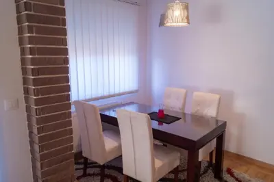 a dining room with a table and white chairs at Apartmani Stanković in Vranje