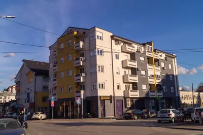 a tall building on a city street with cars parked at Apartmani Stanković in Vranje