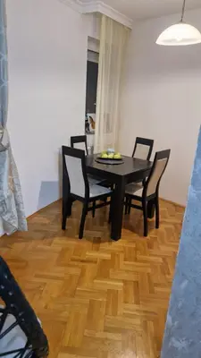 a dining room table with four chairs and a black table at JM Apartman in Donja Vrežina