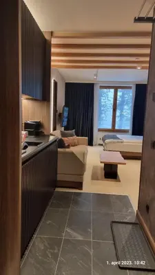 a kitchen and living room with a couch and a table at Woodside Apartments Kopaonik centar in Kopaonik