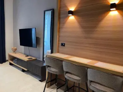 a room with a bar with chairs and a television at Woodside Apartments Kopaonik centar in Kopaonik
