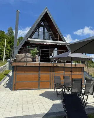 a building with chairs and an umbrella on a patio at Villa Monteverde Goč in Stanišinci