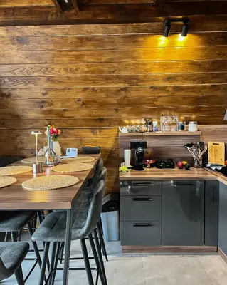 a kitchen with wooden walls and a table with chairs at Villa Monteverde Goč in Stanišinci