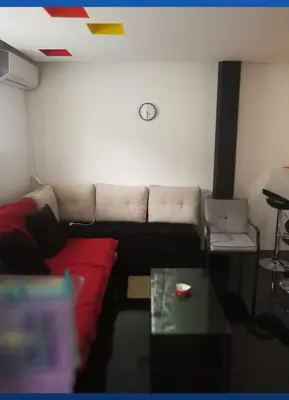 a living room with a red couch and a clock on the wall at Apartman Sokobanja in Soko Banja