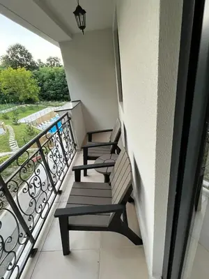 a balcony with three chairs and a view of a yard at Apartman Nika Vb in Vrnjačka Banja