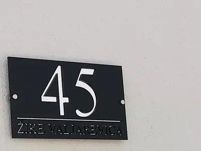 a black sign with the on a wall at Apartman Nika Vb in Vrnjačka Banja