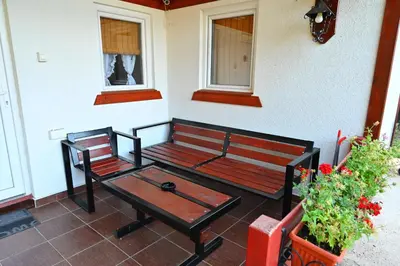 a bench and a table on a porch with flowers at Gocki raj 2 in Goč