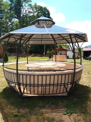 a circular structure with an umbrella on the grass at Gocki raj 2 in Goč