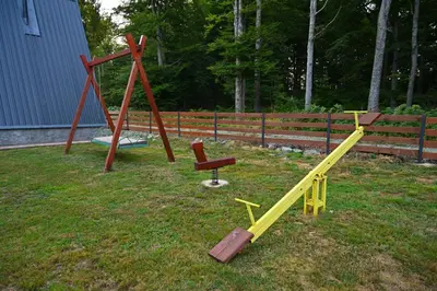 two playground equipment sitting in the grass near a fence at Gocki raj 2 in Goč