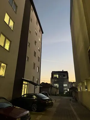 a car parked in a parking lot between two buildings at Urban Apartman-privatan parking- in Kraljevo