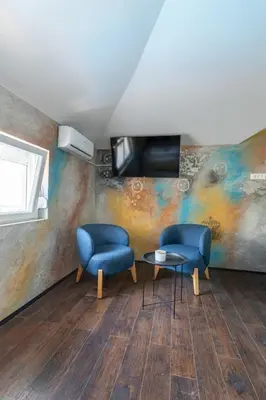 two chairs and a table in a room with a painting at Aleks apartmani in Knjazevac.