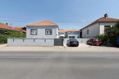 a white house with two cars parked in front of it at Aleks apartmani in Knjazevac.