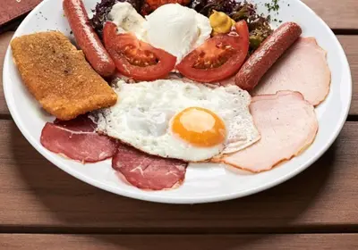 a plate of breakfast food with eggs sausage and tomatoes at HOTEL Crystal Lights in Pirot