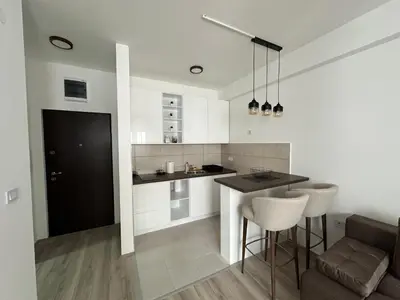 a kitchen with white cabinets and a table and chairs at Aqua apartman 45-2 in Jagodina