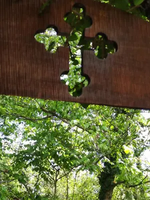 a cross hanging from a building with trees in the background at Seosko turisticko domacinstvo Nikolic-Zivkovic selo Ljubatovica in Čiflik