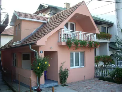 a pink house with a balcony and flowers on it at Apartments Božinović in Soko Banja