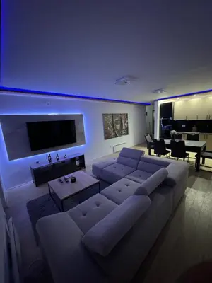 a living room with a large couch and a tv at Brasic Apartman in Zaječar