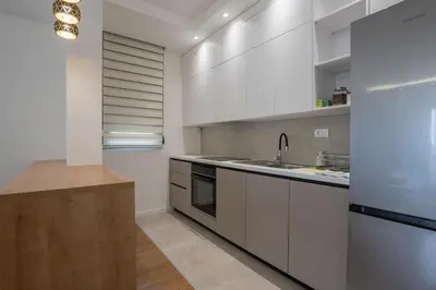 a white kitchen with a sink and a refrigerator at NOVA Apartmani in Kraljevo