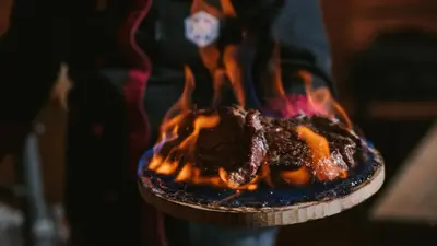 a person is holding a fire in a grill at Rtanj Kopaonik Eco Resort & Spa in Kopaonik