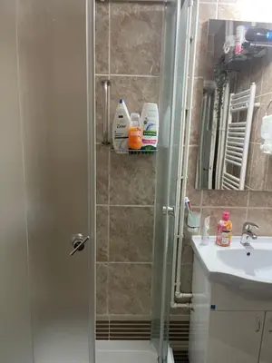 a shower with a glass door next to a sink at VERA apartman in Zaječar