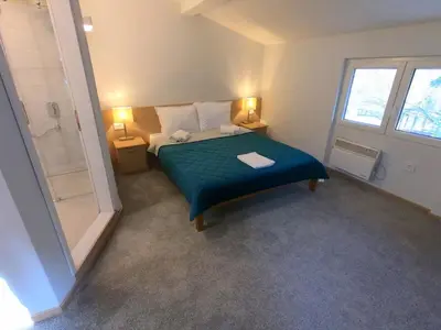 a small bedroom with a bed and a shower at Garni hotel Vir in Vrnjačka Banja