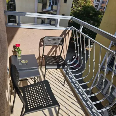 a balcony with chairs and a table with a flower at ONLY 4 YOU apartment in Niš