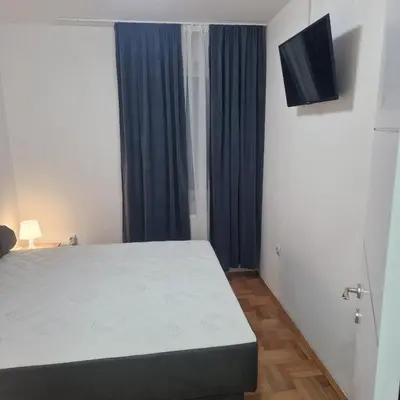 a bedroom with a bed and a television on the wall at ONLY 4 YOU apartment in Niš