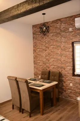a dining room table with chairs and a brick wall at ThEOS in Vranje