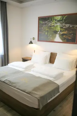 a large bed with white sheets and a painting on the wall at Soko IN Spa in Soko Banja