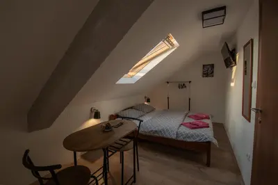 a small bedroom with a bed and a table at Pansion Nana in Aleksandrovac