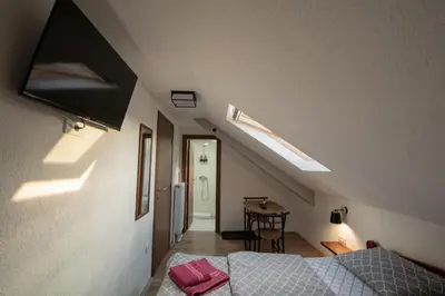 a attic bedroom with a bed and a table at Pansion Nana in Aleksandrovac