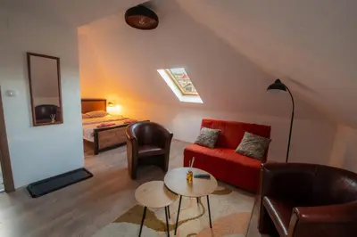 a living room with a red couch and a bed at Pansion Nana in Aleksandrovac