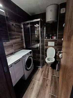 a bathroom with a toilet and a washing machine at Apartman TRAMONTO Kopaonik in Kopaonik