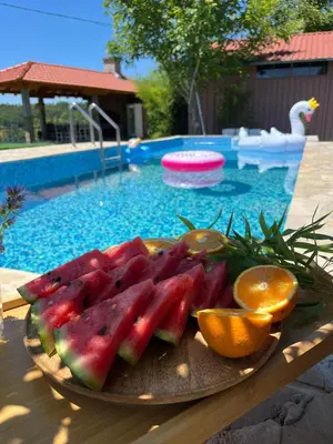 a plate of fruit on a table near a swimming pool at Slatinska idila - kuća sa bazenom in Bunar
