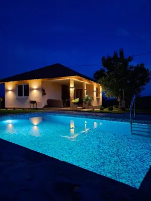 a swimming pool in front of a house at night at Slatinska idila - kuća sa bazenom in Bunar