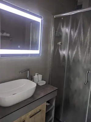 a bathroom with a sink and a shower with a mirror at SokoSTAR Apartman in Soko Banja