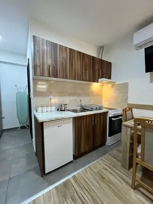 a kitchen with wooden cabinets and a sink and a table at Apartman Nestoria Sokobanja in Soko Banja