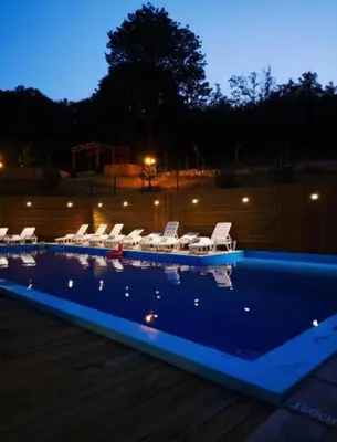 a swimming pool with chairs and a group of lights at Vrnjački Kos in Vrnjačka Banja