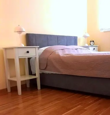 a bed with a nightstand next to a bed with a table at Vrnjački Kos in Vrnjačka Banja