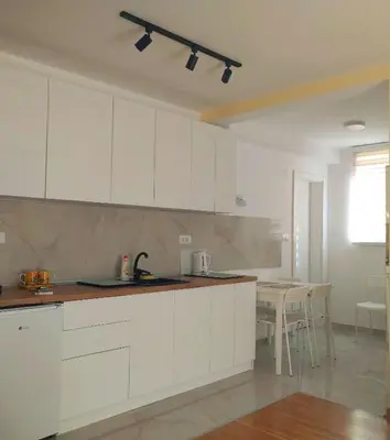 an empty kitchen with white cabinets and a table at Vrnjački Kos in Vrnjačka Banja