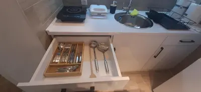 a cabinet with utensils in it next to a sink at ZONA apartman in Vranje