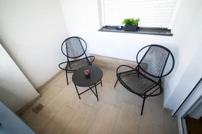three chairs and a table in a room with a window at Apartment sPARK Niš in Niš