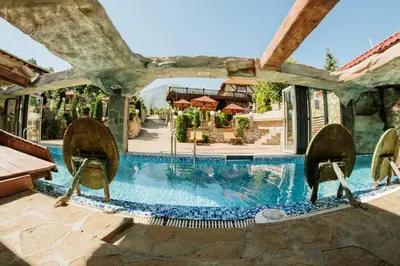 a swimming pool with chairs next to a house at Etno hotel Balasevic Rtanj in Boljevac