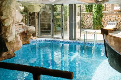 a pool in a house with a rock wall at Etno hotel Balasevic Rtanj in Boljevac