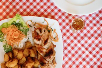 a plate of food with chicken and potatoes on a table at Etno hotel Balasevic Rtanj in Boljevac