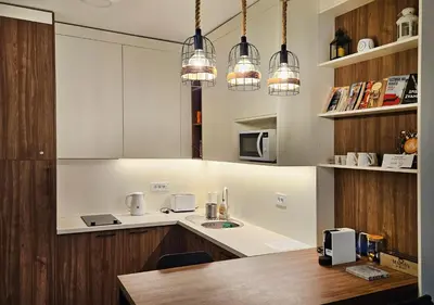 a kitchen with white cabinets and pendant lights at Cozy Mountain Apartment VIDIK in Kopaonik